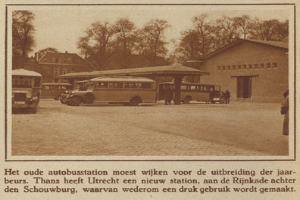 Altes Schwarz-Weiß-Foto eines Busbahnhofs mit mehreren geparkten Bussen, Menschen drumherum, Bäumen und Gebäuden im Hintergrund und Text unten.