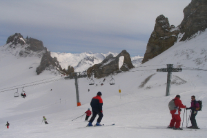Menschen in Pullovern, die auf dem Eis mit Skiern fahren, Seilbahn, Berge und bewölkter Himmel im Hintergrund.
