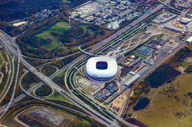 Luftaufnahme des Olympiagel"ndes in M"unchen, Deutschland, umgeben von Geb"uden, B"umen, Stra"en, Fahrzeugen und Gras.
