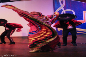 Menschen in Kostümen auf einer Bühne mit einem Vorhang mit Bild dahinter.