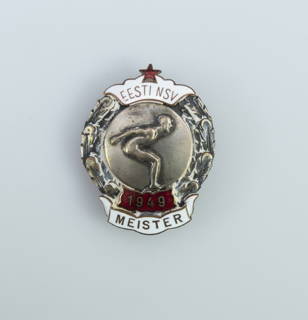 Silberner Anstecker mit rotem Stern, Emblem der Olympischen Spiele 1949 in Deutschland, mit Text in der Mitte auf einem einfarbigen Hintergrund.