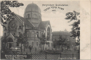 Ein altes Schwarz-Weiß-Foto einer Synagoge in Hamburg, Deutschland, umgeben von Bäumen, Pflanzen und einem Zaun, mit ein paar Menschen davor und Text auf der Postkarte.