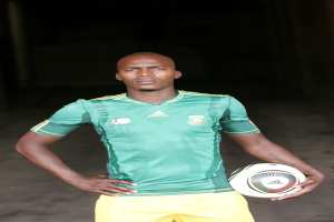 Ein Mann in einem Fußballtrikot, der einen Fußball in der Hand hält.