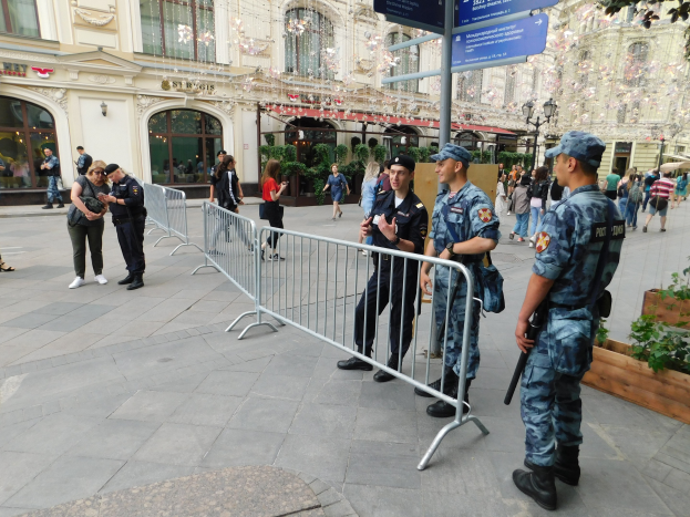 Polizeibeamte in Uniform stehen hinter Barrikaden und blicken auf eine Menge, von der einige Kapuzen tragen und Waffen halten, während sie einen Anti-Terror-Einsatz in Wien, Österreich, durchführen.