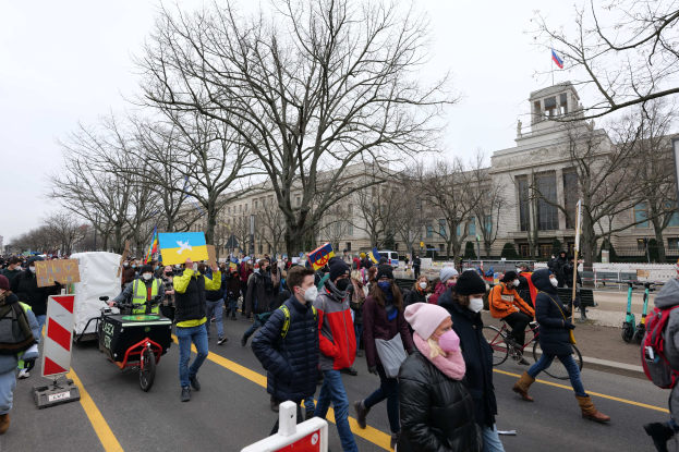 Eine große Gruppe von Menschen marschiert auf einer Demonstration in Washington, D.C. am 21. Januar 2020, einige halten Schilder und fahren Fahrräder, mit Bäumen und einem klaren blauen Himmel im Hintergrund.