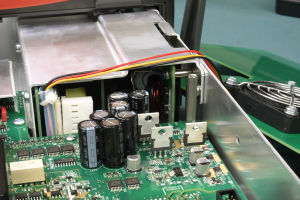 Nahaufnahme einer Leiterplatte mit angeschlossenem Netzteil, das elektronische Bauteile wie Batterien und Drähte enthält.