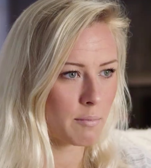 Blonde Frau mit blauen Augen im Vordergrund, die besorgt aussieht mit einem unscharfen Hintergrund.