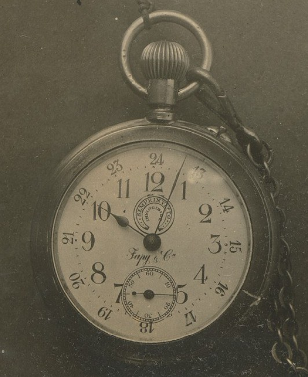 Altes Schwarz-Weiß-Foto einer Taschenuhr mit einer Kette, das eine nummerierte Zifferblat zeigt.