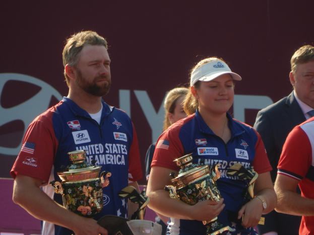 Gruppe von Menschen mit Trophäen vor dem Hintergrund eines Schildes mit der Aufschrift "World Archery Championships"