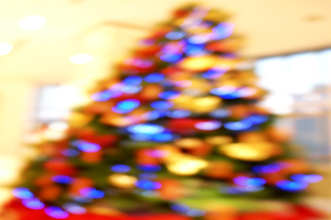 Eine unscharfe Innenaufnahme mit einem Weihnachtsbaum in der Mitte, der mit Lichtern und Schmuck verziert ist.