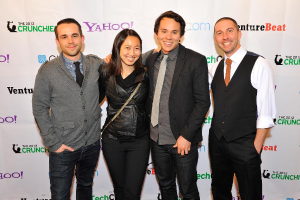 Eine Gruppe strahlender Individuals posiert vor der Kamera mit einem Sponsorenbanner im Hintergrund.