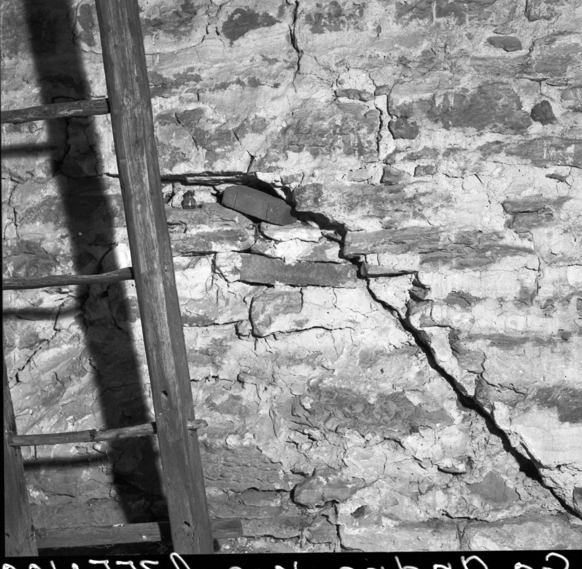 Schwarz-weiß-Foto einer Leiter, die an einer zerbrochenen Wand lehnt, mit Text am unteren Rand.
