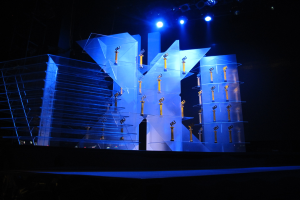 Bühne für eine Preisverleihung mit dunklem Hintergrund und minimaler Beleuchtung, mit wenigen Objekten auf der Bühne.