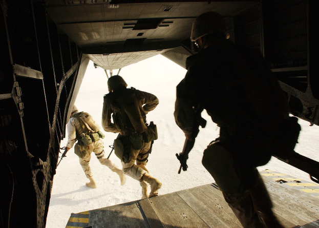 Soldaten in Uniform und Helmen steigen aus einem Flugzeug und halten Gewehre.