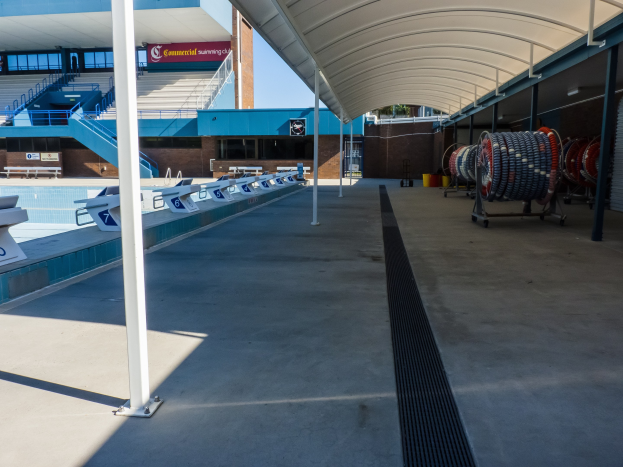 Großer Hallenbad mit zahlreichen Stühlen, einem Gebäude im Hintergrund, Polen links und verstreuten Objekten rechts an der University of Texas at Austin.