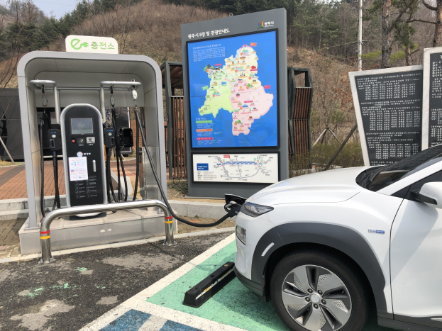 Elektroauto-Laden an einer Station in Seoul, Südkorea, mit Bäumen und Himmel im Hintergrund.