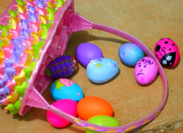 Ein Korb mit mehreren bunten Ostereiern, der an einer Wand lehnt.