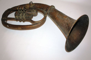 Alter Messinghorn mit glänzendem Finish, gebogenem Hals und aufgeblähtem Trichter, verziert mit kunstvollen Gravuren, auf einem weißen Hintergrund.