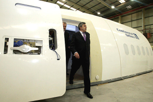 Ein Flugzeug-Prototyp mit der Aufschrift "Continental Airlines", mit zwei Personen daneben, vor einer Wand, Lichtern und einigen anderen Gegenständen.