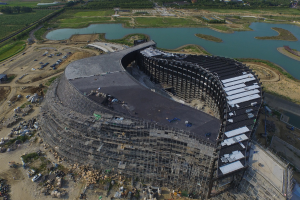 Ein Gebäude, ein Gewässer mit Gras am Ufer und ein Auto.