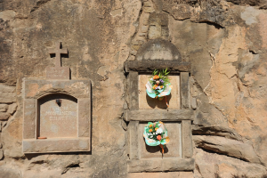 Memorials in eine Wand gemeißelt mit Blumensträußen davor.