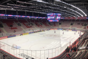 Eishockeyspiel in einer großen Arena zwischen den St. Louis Blues und den Detroit Red Wings, mit Zuschauern, die auf Stühlen sitzen und in der Nähe der Eisfläche stehen.
