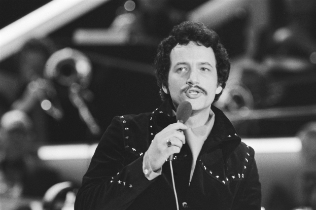 Schwarzes und weißes Foto von Elvis Presley, der ein Mikrofon hält, mit einem unscharfen Hintergrund.