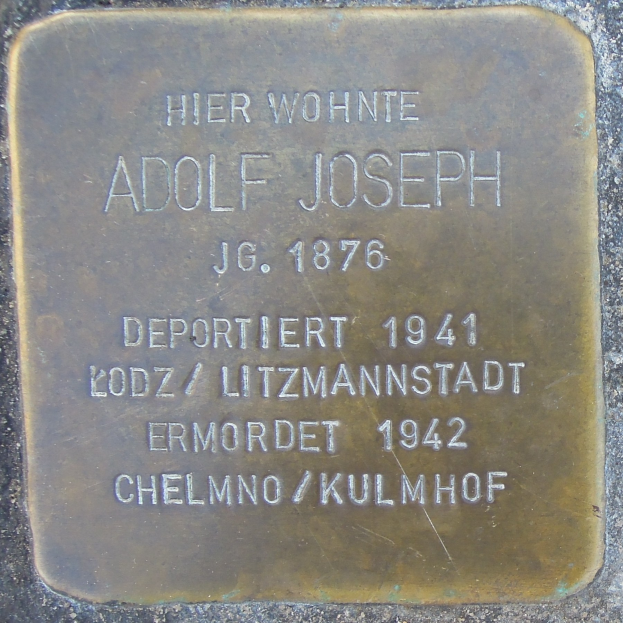 Metallplatte an der Seite eines Gebäudes mit der Inschrift "Adolf Joseph"