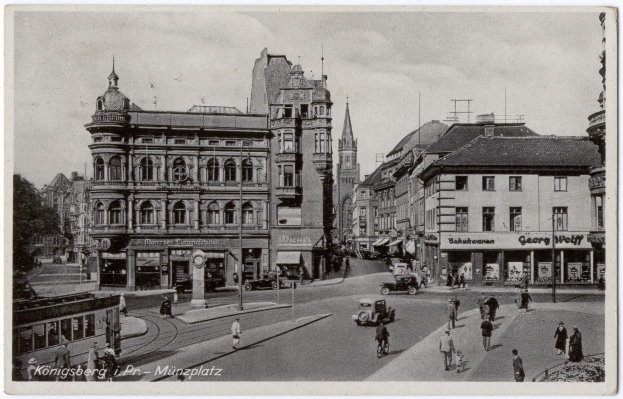 Schwarz-weiß-Foto einer belebten Münchner Stadtstraße mit Fußgängern, Fahrzeugen, Gebäuden, Bäumen und Himmel, mit Text unten.