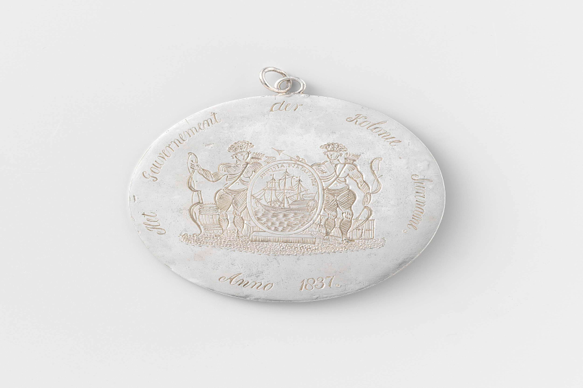 Eine Silbermedaille mit eingravierten Bildern eines Mannes und einer Frau vor einem weißen Hintergrund, die das Jubiläum der Deutschen Revolution feiern.