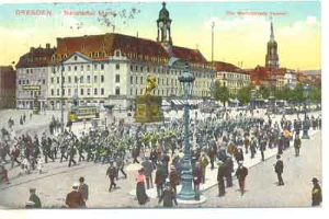 Eine alte Ansichtskarte zeigt einen belebten Stadtplatz in Dresden, Deutschland, mit Menschen, einem zentralen Denkmal und Gebäuden mit Fenstern im Hintergrund unter einem bewölkten Himmel, zusammen mit Text auf der Ansichtskarte.