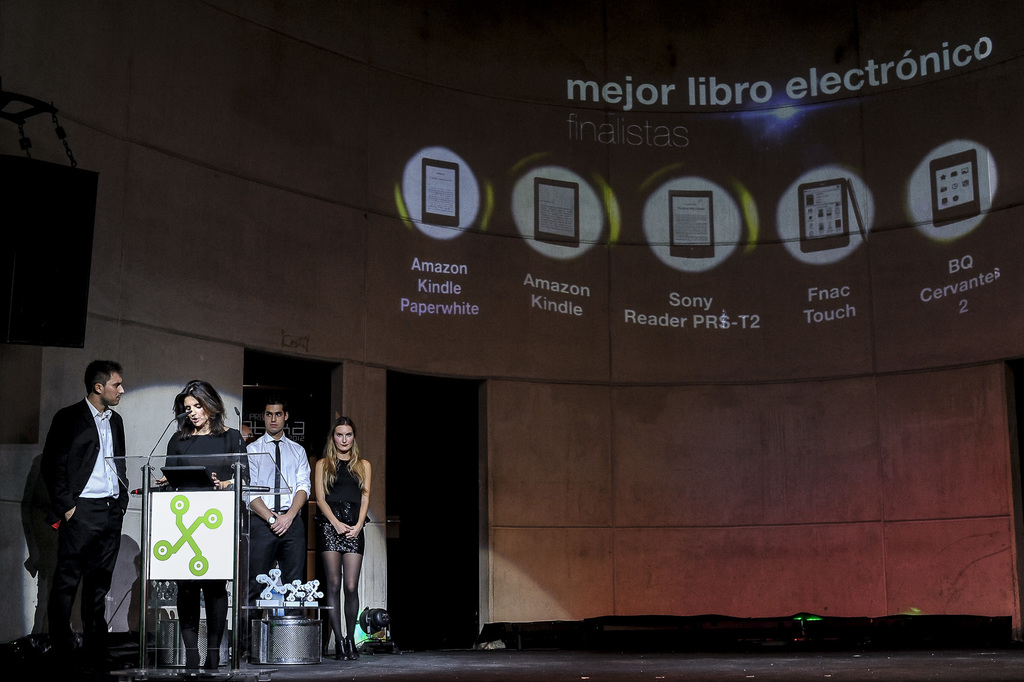 Vier Personen stehen links, wobei eine Frau einen Vortrag hält; im Hintergrund sind Bilder von Gadgets mit ihren Namen darunter angezeigt.