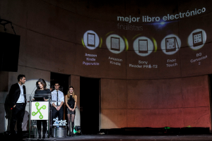 Vier Personen stehen links, wobei eine Frau einen Vortrag hält; im Hintergrund sind Bilder von Gadgets mit ihren Namen darunter angezeigt.