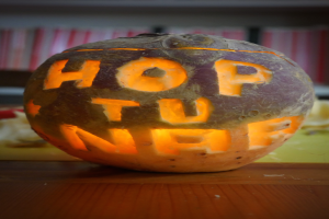 Eine Kürbis mit den Worten "hop you off" eingeschnitzt, auf einem Tisch mit einem unscharfen Hintergrund.