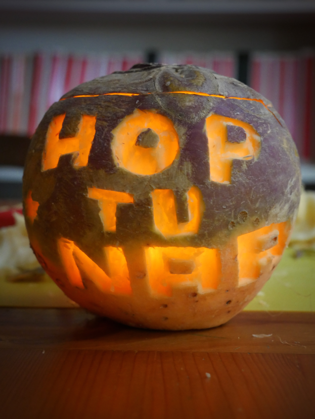 Eine Kürbis mit den Worten "hop you off" eingeschnitzt, auf einem Tisch mit einem unscharfen Hintergrund.