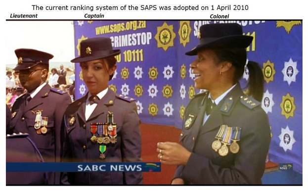 Gruppe von Menschen in Uniformen und Hüten, die vor einer Tafel mit der Aufschrift "Das aktuelle Ranglistensystem der SAP wurde am 1. April 2010 übernommen" stehen.