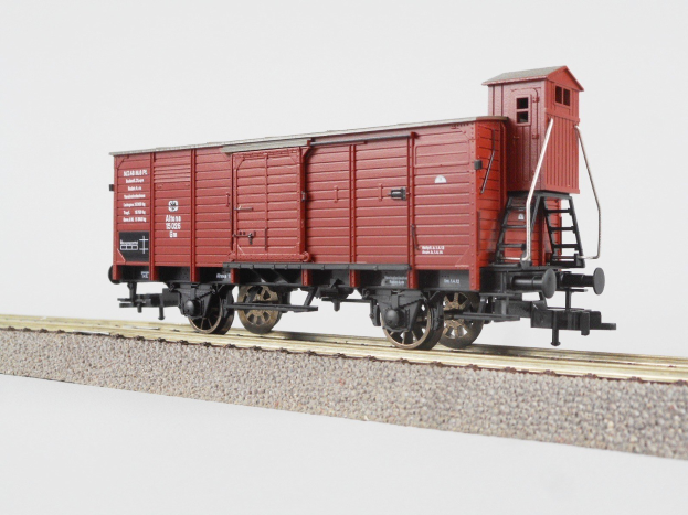 Roter Zug-Gepäckwagen auf einer Schiene vor einem weißen Hintergrund mit Text an der Seite.