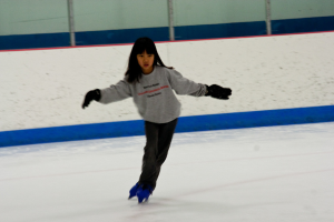 Eine Person in Kleidung fährt auf dem Eis mit Stöcken am oberen Bildrand