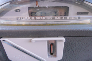 Ein Parkautomat mit der Aufschrift "Maximale Parkdauer 4 Stunden" und einem Münzschlitz mit einer Münze.