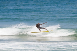 Ein Mann steht auf einem Surfbrett und reitet eine Welle im Wasser.