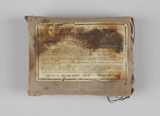 Kleiner Verbandskoffer mit einer Informationsschrift obenauf.